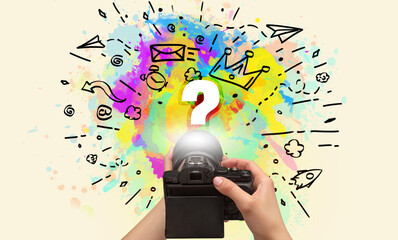 Close-up of a hand holding digital camera with abstract drawing and ? inscription