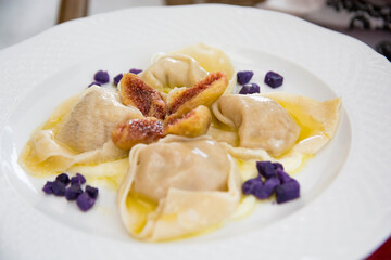 Ravioli with ricotta cheese, figs and purple sweet potatoes, served in a white plate, Italy