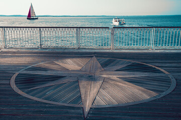 View to the sea with small yacht and wooden compass