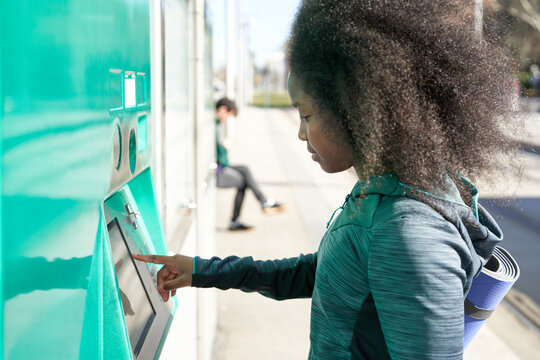 Sportive woman buying ticket at automatic machine