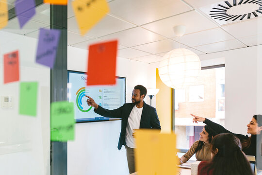 Black man presenting report on TV to coworkers in office