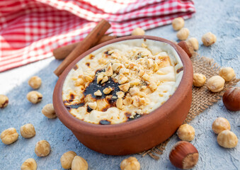 Baked rice pudding turkish milky dessert sutlac in earthenware casserole with hazelnuts