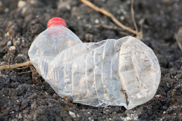 Obraz premium Environmental pollution: An empty plastic bottle of water, left as trash over the ground