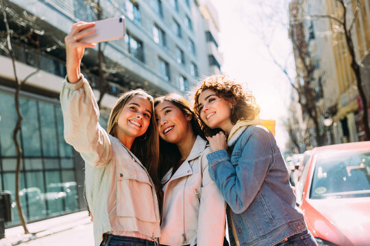 Multiracial female friends taking selfie in city