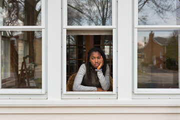 Bored black girl looking out her window