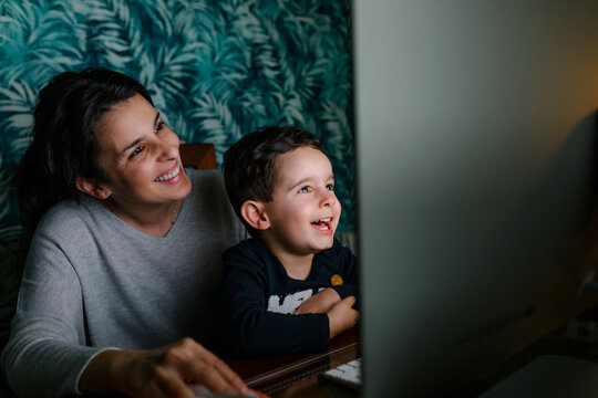 Mother and son having fun while using a computer at night