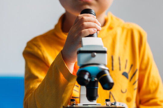 Little anonymous kid using a toy microscope