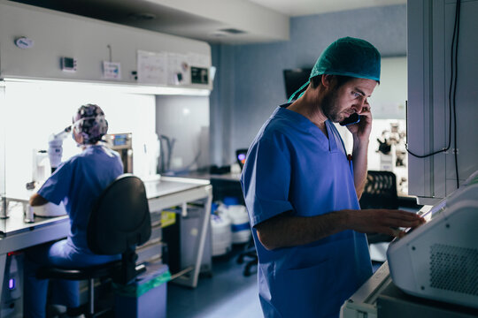 IVF Biologist on phone while manipulating an incubator