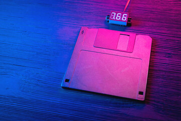 A floppy disk diskette in the neon lights on the black table background.