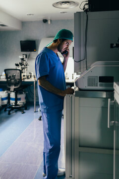 IVF Biologist on phone while manipulating an incubator