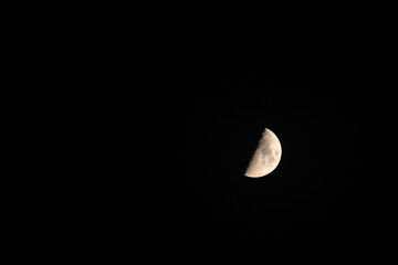 Half moon phase on black clear sky. Lunar surface glow