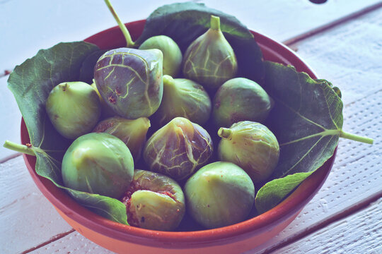 Higos verdes sobre sus hojas en un bol de barro, frutas de temporada
