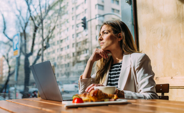 Concentrated businesswoman using laptop in cafeteria