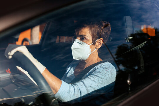 Senior woman driving car with mask