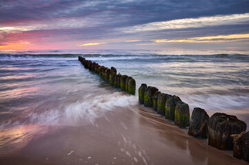 Old wooden breakwater at purple sunset, Baltic Sea coast, Poland.