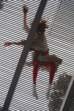 bottom view of a girl in red tights and a beige cloak lying on the trellised floor