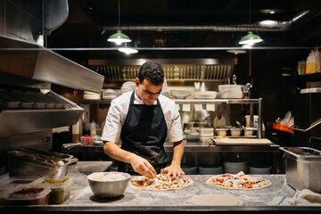 Cook preparing a pizza in a restaurant's kitchen