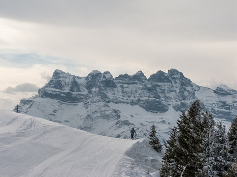 A lone skier rests at the ridge of the slope looking at the spectacular view of les dents du midi, the Alps