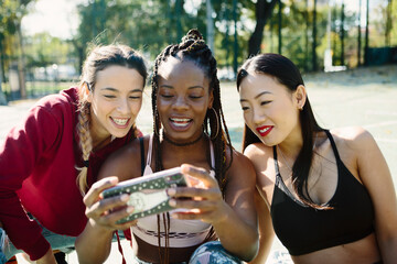 Three friends looking at a cell phone sitting on the ground