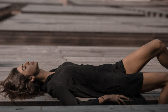 side view of a beautiful dark-haired girl lying on a wooden bench