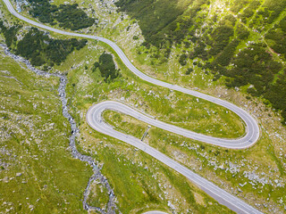 Winding road from high mountain pass, in summer time. Aerial view by drone . Romania
