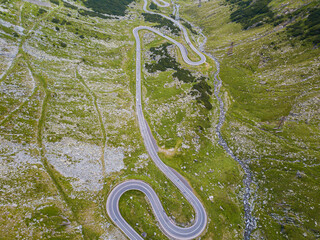 Winding road from high mountain pass, in summer time. Aerial view by drone . Romania