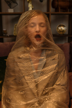 Portrait of a girl in a plastic bag choking in a room