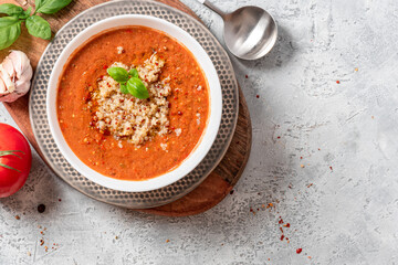 Gazpacho with quinoa. Cold tomato soup with quinoa, peppers, cucumbers, olive oil and spices in a white bowl on a gray concrete background top view. Vegan and vegetarian food, Mediterranean cuisine.