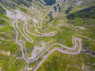 Winding road from high mountain pass, in summer time. Aerial view by drone . Romania
