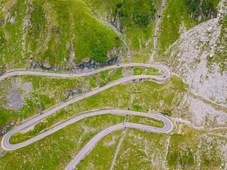 Winding road from high mountain pass, in summer time. Aerial view by drone . Romania