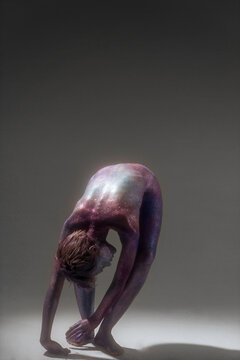 Beautiful slim model in space bodypainting posing bent over in a dance pose