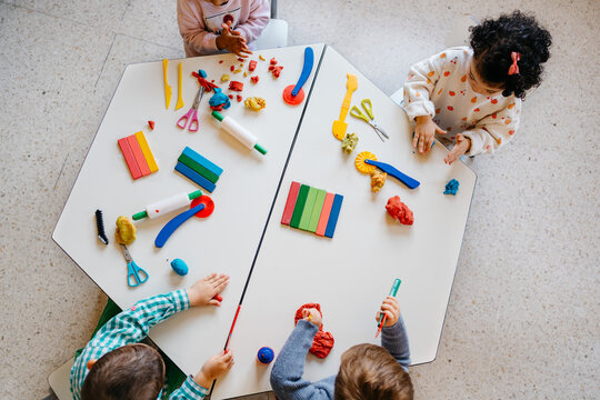 Top view of iverse kids playing with modeling clay - Powered by Adobe