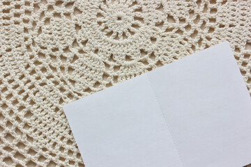 white blank card on a lace tablecloth, top view.