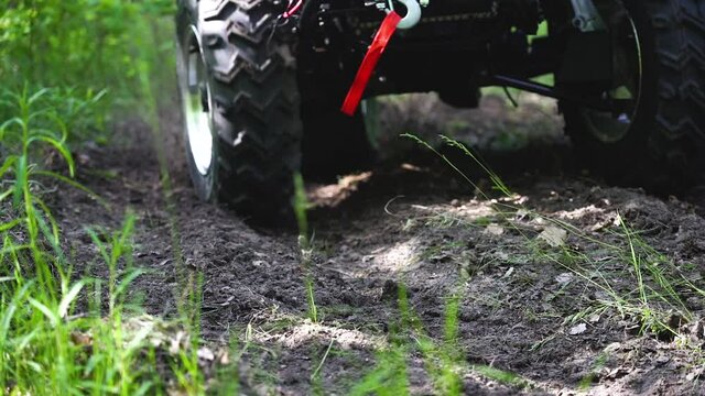 Close-up. Slowmotion. The wheels of the ATV drive along the dirt road. ATV Wheels. Dirt flies from the wheels of the ATV. Dirt from the wheels.