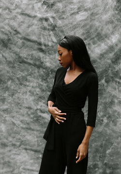 Portrait of a black woman in black outfit over grey background