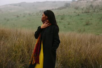 black woman with coat outdoors looking to the side