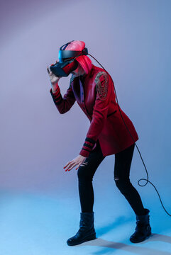 A girl with pink hair in a red jacket and VR Headset in the color light touches something in the air