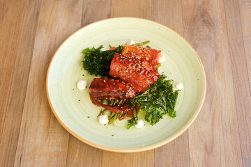 cooked octopus presented in plate on wooden background. top view