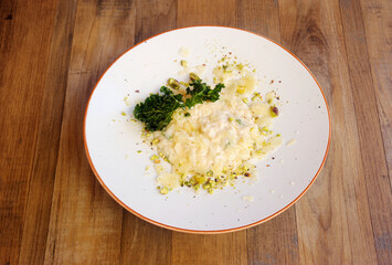 risotto with pistachios presented in plate on wooden background. top view