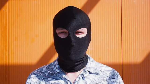 The man removes the black balaclava from his face. Disclosure of the confidentiality of a person's identity. Open face.