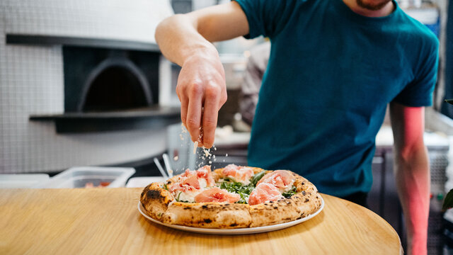 Preparing pizza in a restaurant - Powered by Adobe