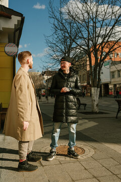 Two stylish guys chat on the street