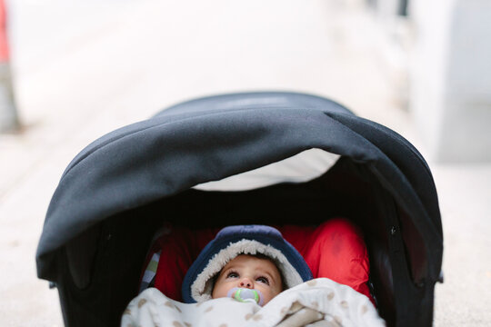 Kid on stroller with dummy in winter