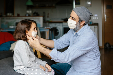 Father adjusting face mask to his daughter