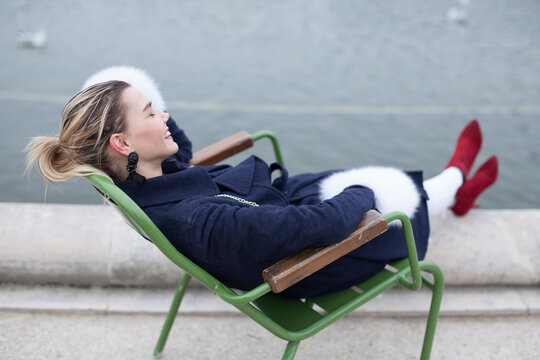 Girl in paris laughing sitting on the chair outside at winter