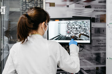 Back view of unrecognizable pharmacist operating modern robot in pharmacy