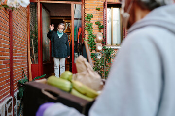 Woman waving at a man delivering food