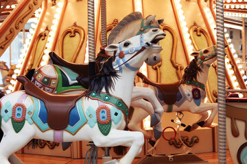 Fototapeta na wymiar Horses on a traditional fairground Children’s carousel. Wooden horses spin around the post. Joy for children.