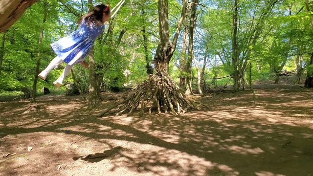 Adorable girl having fun on a swing on summer day, in Epping Forest, Loughton, London