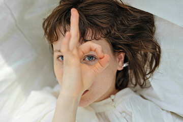portrait of a girl looking through the okay sign